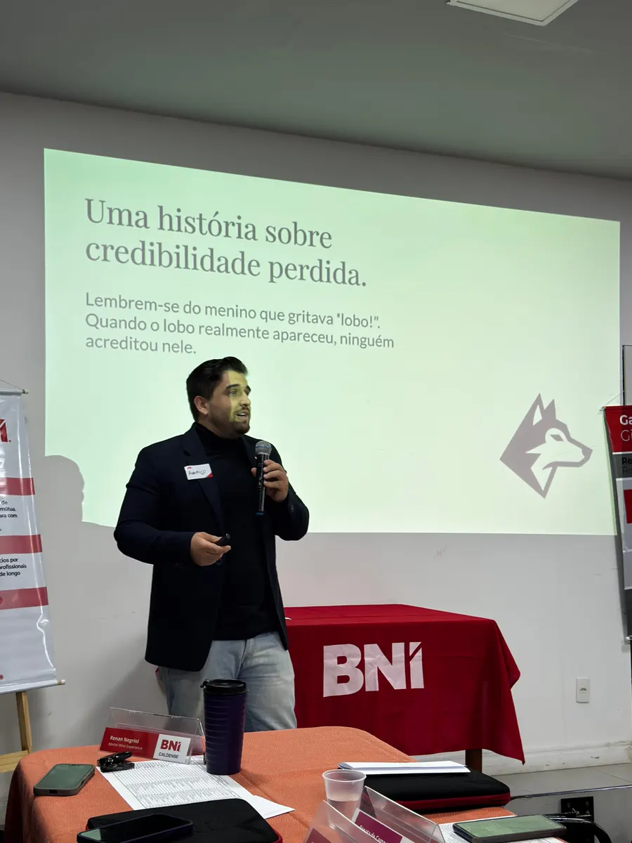 Rodrigo Neves com microfone durante uma palestra, ao lado do telão